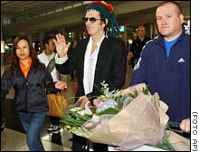El guitarrista Keith Richards saluda al llegar al aeropuerto de Hong Kong.