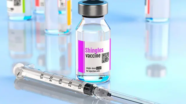 Botella de vacuna contra herpes zóster junto a una jeringa