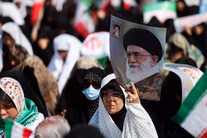Mujeres sosteniendo carteles del líder fallecido Ali Khamenei