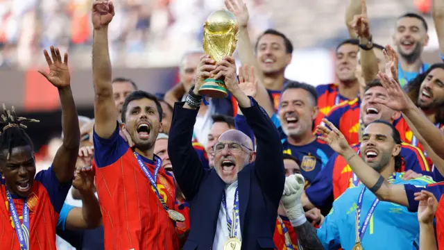 El seleccionador de España, Luis de la Fuente, levanta el trofeo de la Copa del Mundo mientras el equipo celebra.
