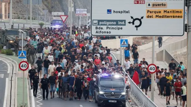 Agentes de policía y soldados españoles escoltan a migrantes